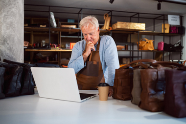 Small business owner reviewing finances on a laptop in a workshop, representing succession planning with a Grand Junction CPA firm
