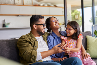 Family members working together and laughing on a couch while discussing business ideas