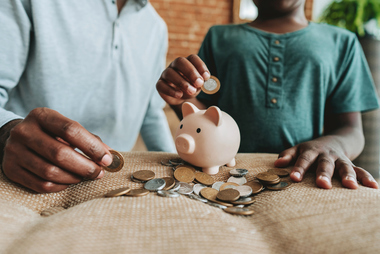 Child and parent placing coins into a piggy bank to build long-term savings through a Trump Account