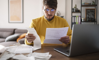 Person reviewing bills and financial documents related to canceled debt and taxes.