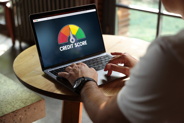 Person reviewing a credit score on a laptop as part of improving their financial health